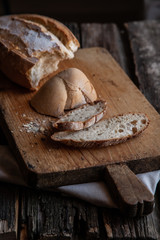 Fresh bread slice and cutting knife on rustic table