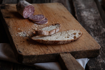 Fresh bread slice and cutting knife on rustic table