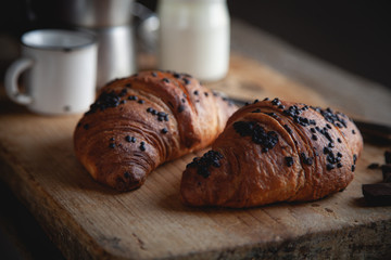 Croissant with chocolate and coffee on the wooden table