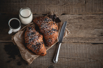Croissant with chocolate and coffee on the wooden table