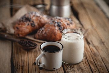 Croissant with chocolate and coffee on the wooden table
