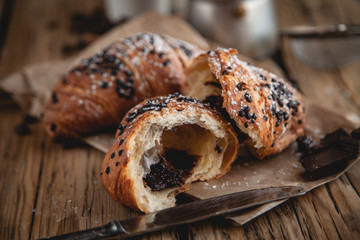Croissant with chocolate and coffee on the wooden table