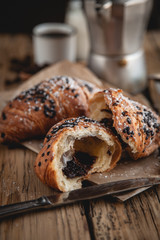 Croissant with chocolate and coffee on the wooden table