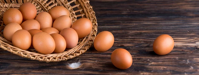 Tuinposter chicken eggs in a straw tray on an old wooden table © Rakursstudio