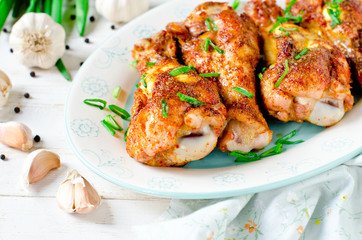 Baked chicken legs on a plate on a white wooden table