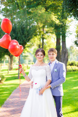 Happy newlyweds with red balloons close up