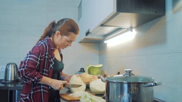 woman in the kitchen preparing a meal concept. girl in the kitchen cuts cabbage with a knife. cook vegetarian food healthy food. lifestyle girl at home in the kitchen slow motion video