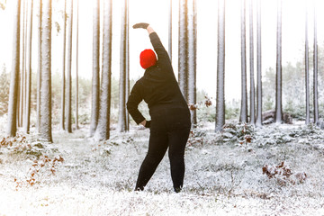Plus size woman doing exercises in winter forest. Outdoor fitness.