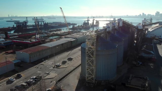 An aerial view of silos in the North Vancouver cargo terminal and trainyard with a view of downtown Vancouver.
