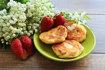 Spring bouquet lily of the valley, Cheesecakes with strawberries. Breakfast of cottage cheese cheesecakes. Spring breakfast.