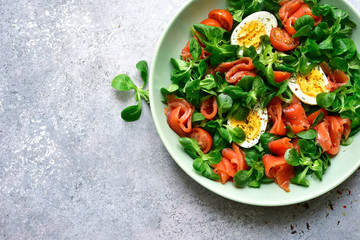 Green salad with salted salmon, tomato and boiled eggs.Top view with copy space.