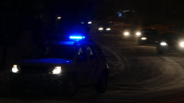 Police car with flashing lights going on the road in winter.