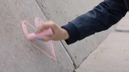 young woman hand drawing heart using pink chalk happy teenage girl in love on valentines day concept