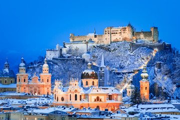 Salzburg, Austria: Winter view of the historic city of Salzburg with famous Festung Hohensalzburg and Salzach river illuminated in beautiful twilight during scenic Christmas time in winte