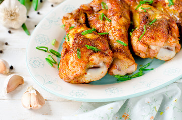 Baked chicken legs on a plate on a white wooden table