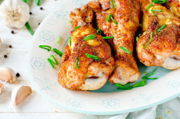 Baked chicken legs on a plate on a white wooden table