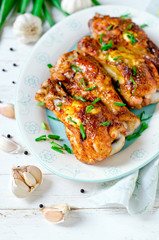 Baked chicken legs on a plate on a white wooden table