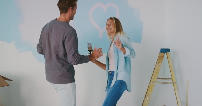 Happy young couple dancing together in new home, cute painting dancing, home improvement
