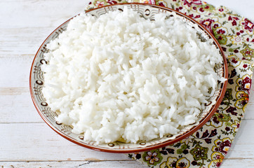Boiled rice in a plate on a white wooden table