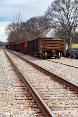 Obraz premium Two railroad tracks and rail cars travelling the distance.