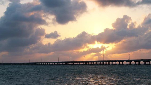 Dramatic orange cloudy sunset at seascape of Bahia Honda State Park in Florida Keys with old seven mile railroad bridge, overseas highway at gulf of mexico, clouds moving 