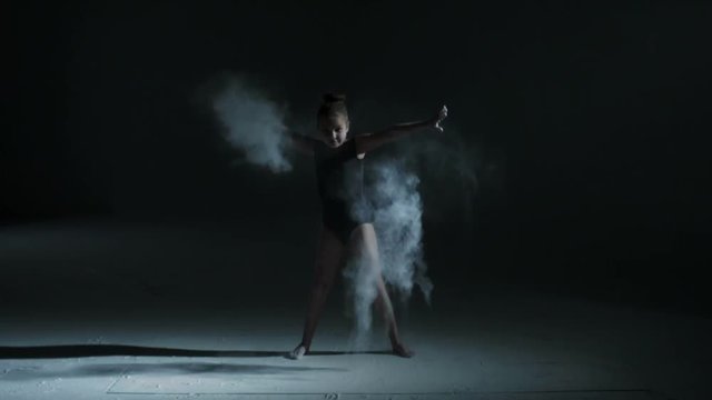 Silhouette of freestyle dancing young girl using powder in dance moves