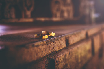 two wedding rings, golden color, on brick wall. Romantic photo with alliance, engagement,...