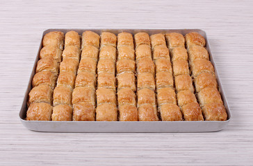 Baklava with walnuts with a tray on a white stripe table