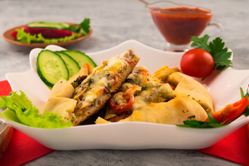 Pizza with mushrooms and cheese in a white plate. Chopped fresh vegetables. Quick delicious dinner. Spicy tomato sauce.