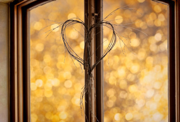 valentine's heart made of twigs in window against golden bokeh