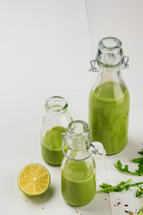Fresh made healthy green smoothie served in bottles on white background. Fruits and vegetables and seeds ingredients around. Close with copy space. Lifestyle.