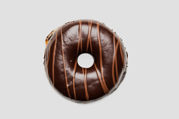 Chocolate glazed doghnut with chocolate milk lines on white background. High resolution image for food industry.