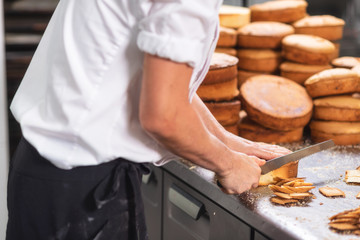 pastry chef cutting the sponge cake on layers. Cake production process .