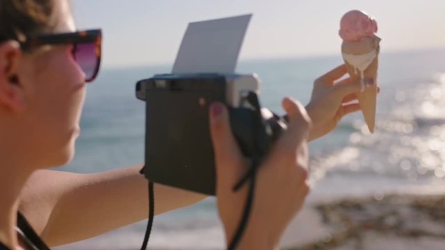 young woman taking photo on beach using old camera