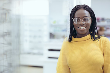 Young pretty african woman choosing prescription glasses frames in Optician's shop.