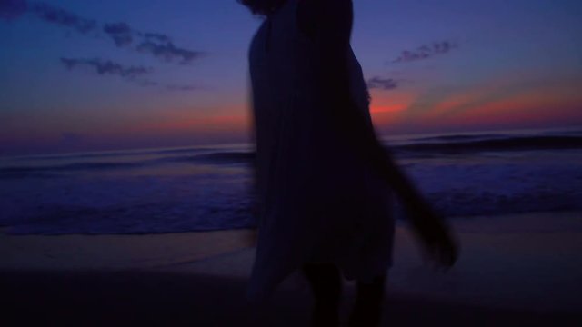 Silhouette of ethnic female enjoying vacation beach at sunset
