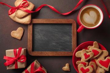 Naklejka na ściany i meble Valentine's Day with a cup of coffee, a board, a heart-shaped cookie, a gift. Top view with copy space