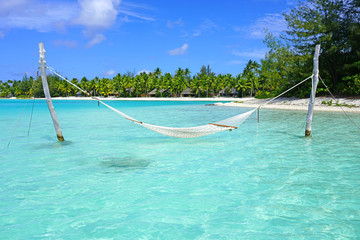 Fototapeta na wymiar Hammock with a view, planted in the azure waters of the Bora Bora lagoon, French Polynesia 
