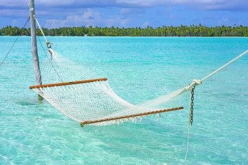 Hammock with a view, planted in the azure waters of the Bora Bora lagoon, French Polynesia  - obrazy, fototapety, plakaty