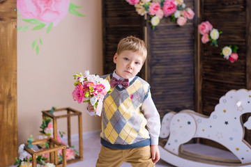 Funny boy with blond hair holds a bouquet