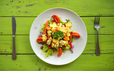Flat lay chicken salad on round plate with knife and fork.