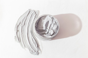 Natural face mask. Smear Clay Mask for face and container with mask on a light background with a shadow. Top view. 