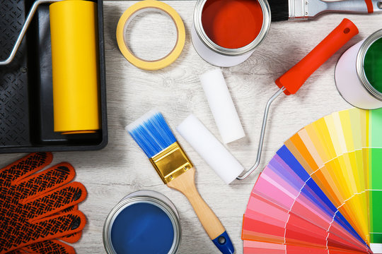 Flat lay composition with cans of paint and decorator tools on wooden background