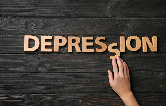 Woman making word Depression with letters on dark wooden background, top view
