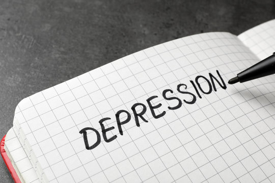 Writing word Depression in notebook on table, closeup
