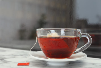 Glass cup of hot tea on window sill. Space for text