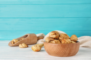 Wooden bowl with dried figs on table, space for text. Healthy fruit