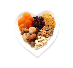 Heart shaped plate with different dried fruits and nuts on white background, top view