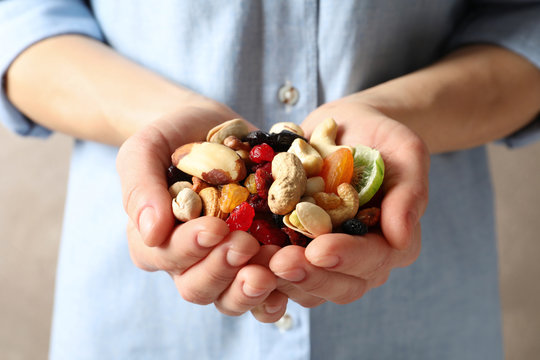 Young woman holding handful of different dried fruits and nuts, closeup