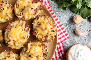 Flat lay composition with plate of baked potatoes and sauce on grey background